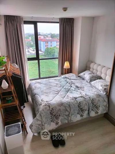 Cozy bedroom with large window offering scenic view, featuring stylish decor and comfortable bedding.