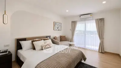 Spacious bedroom with modern decor and large window offering natural light and scenic views.