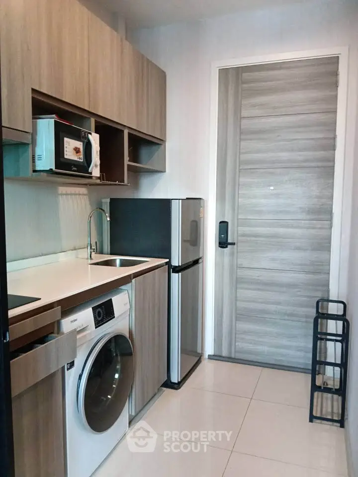Modern compact kitchen with washing machine and microwave in stylish apartment