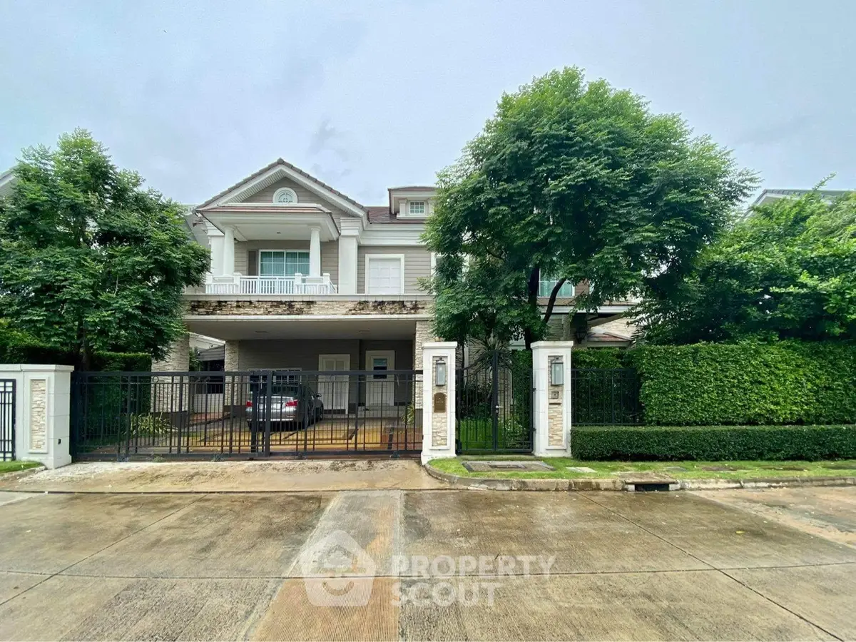 Elegant two-story house with lush greenery and gated entrance in a serene neighborhood.