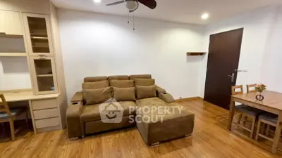 Cozy living room with brown sofa, wooden floor, and modern ceiling fan.
