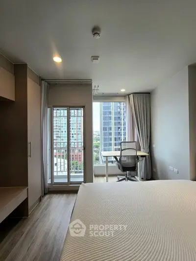 Modern bedroom with city view, featuring a study desk and large windows for natural light.
