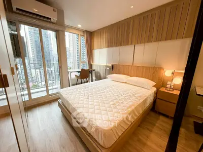 Modern bedroom with city view, featuring a cozy bed and stylish decor in a high-rise apartment.