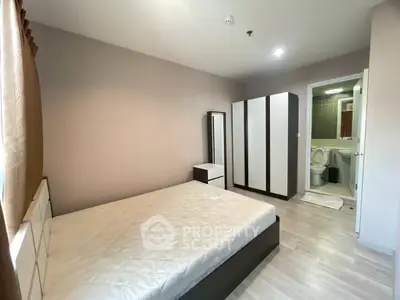 Modern bedroom with ensuite bathroom and sleek wardrobe in a cozy apartment.