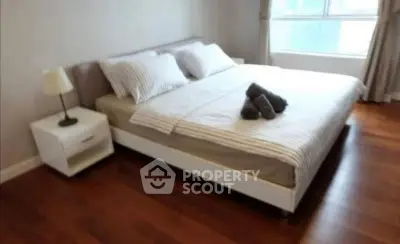 Spacious bedroom with elegant wooden flooring and large window for natural light.