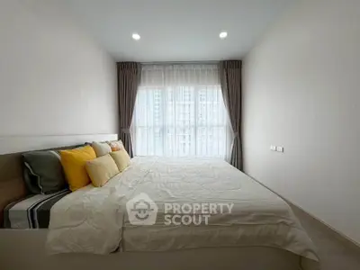 Spacious bedroom with large window and modern decor in a high-rise apartment.
