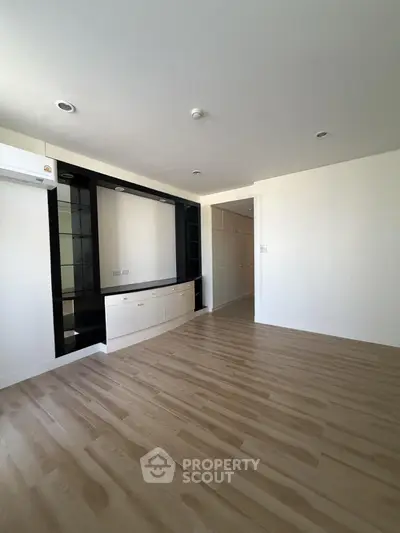 Spacious modern living room with sleek wooden flooring and built-in storage, perfect for contemporary living.