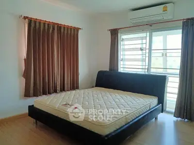 Spacious bedroom with large windows and modern air conditioning unit, perfect for comfort and relaxation.