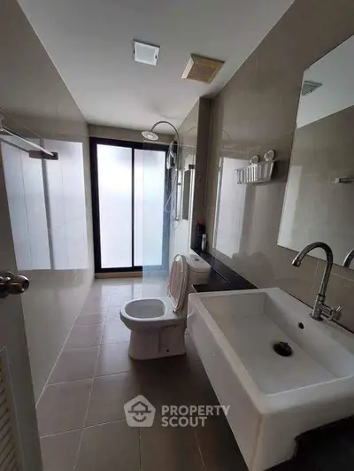 Modern bathroom with sleek fixtures and large frosted window for natural light.