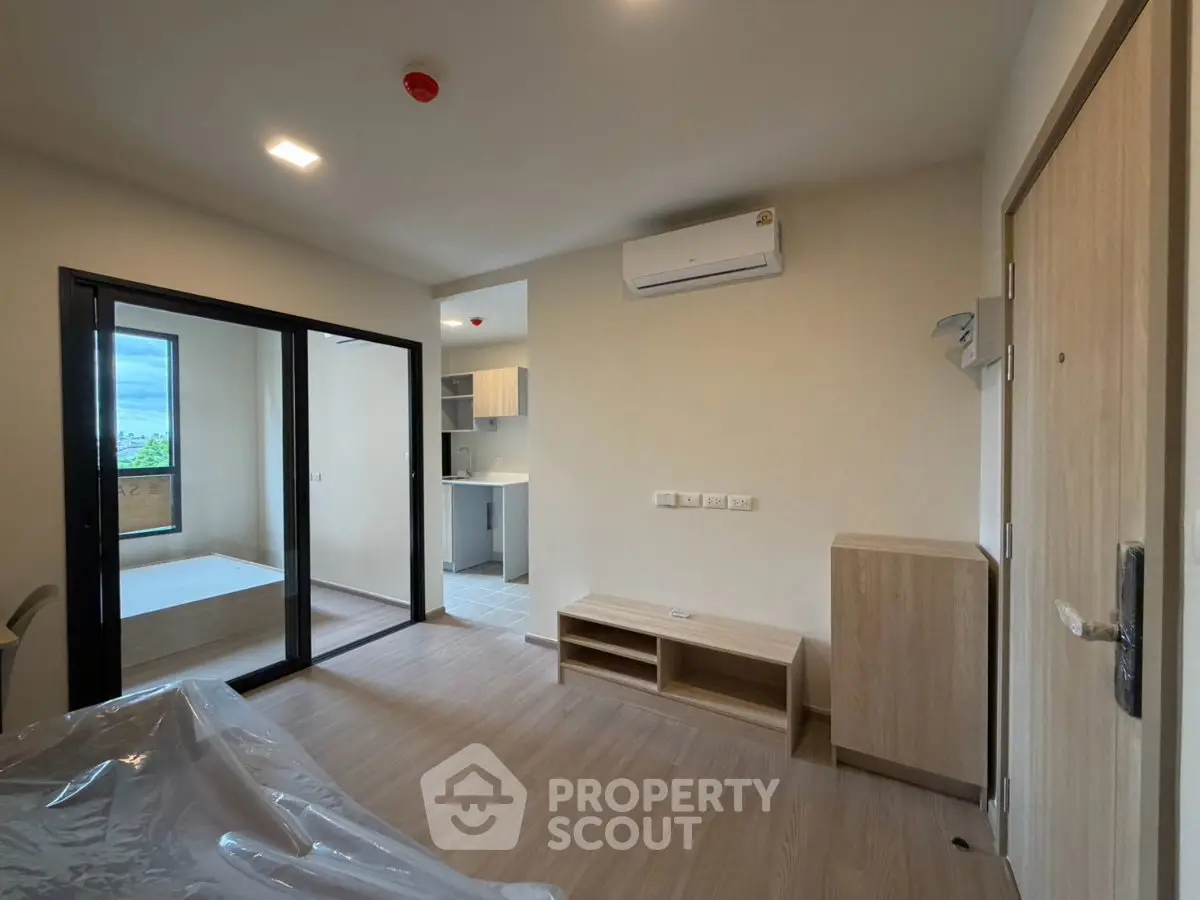 Modern living room with open layout and natural light, featuring air conditioning and wooden flooring.