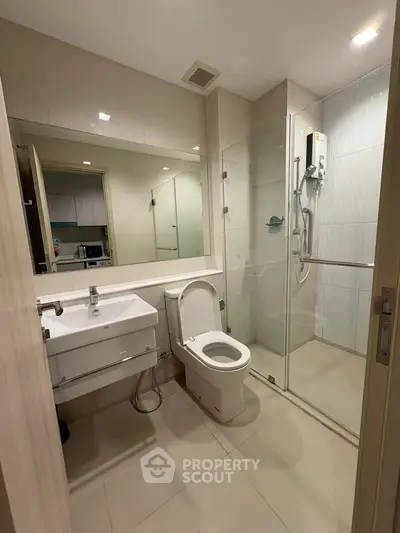 Modern bathroom with glass shower and sleek fixtures in contemporary apartment.
