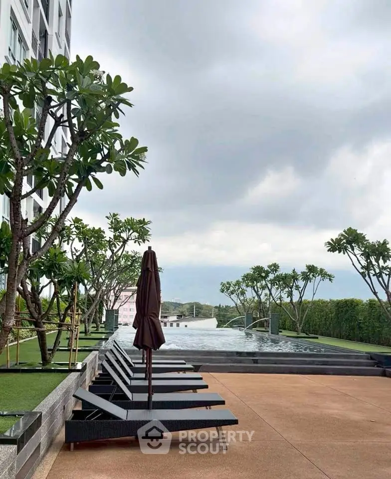Luxurious poolside area with sun loungers and lush greenery in a modern residential complex.