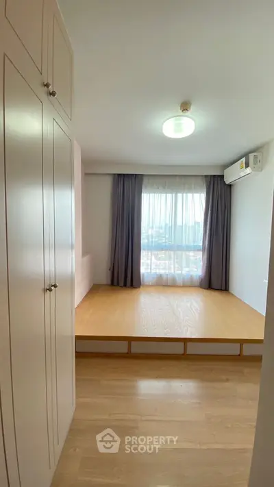 Spacious bedroom with large window and built-in wardrobe, offering a bright and airy atmosphere.