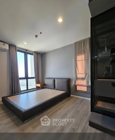 Modern bedroom with large window and minimalist design in high-rise apartment.