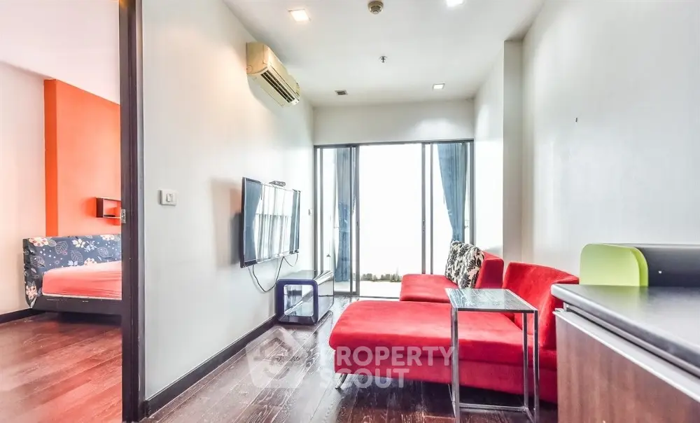 Modern living room with red sofa and wall-mounted TV in bright apartment