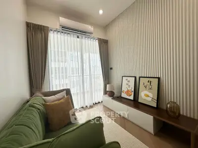 Stylish living room with green sofa and modern decor, featuring large window and elegant curtains.