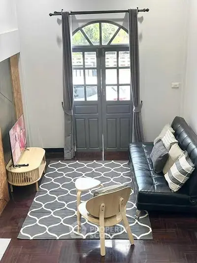 Charming living room with modern decor, featuring a cozy sofa, stylish rug, and natural light from large windows.