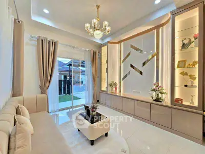 Elegant living room with chandelier and modern decor, featuring large windows and stylish shelving.