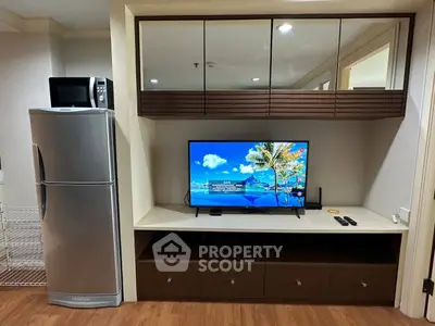 Modern living room with sleek TV unit and stainless steel fridge, perfect for urban living.