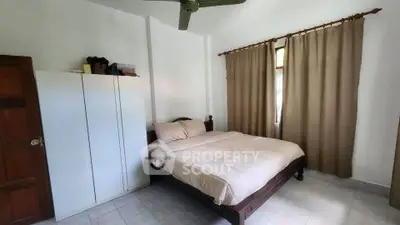 Cozy bedroom with double bed, wardrobe, and ceiling fan, featuring natural light and neutral decor.