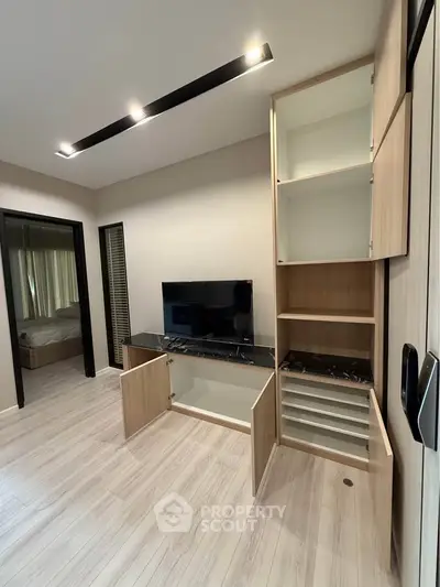 Modern living room with sleek built-in storage and TV unit, showcasing minimalist design and functionality.