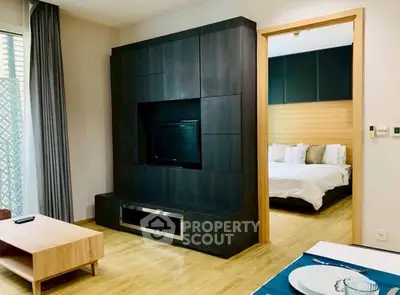 Modern living room with sleek entertainment unit and view into cozy bedroom