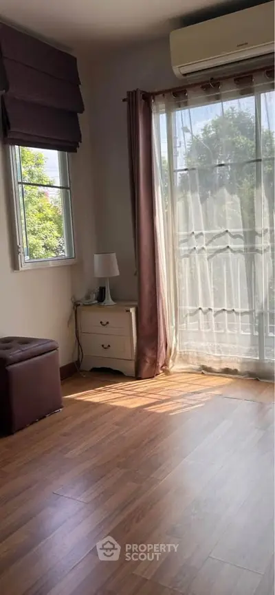 Bright room with wooden flooring and large window, perfect for cozy living.