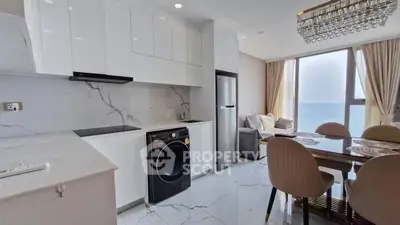 Modern kitchen with ocean view, sleek appliances, and elegant dining area.