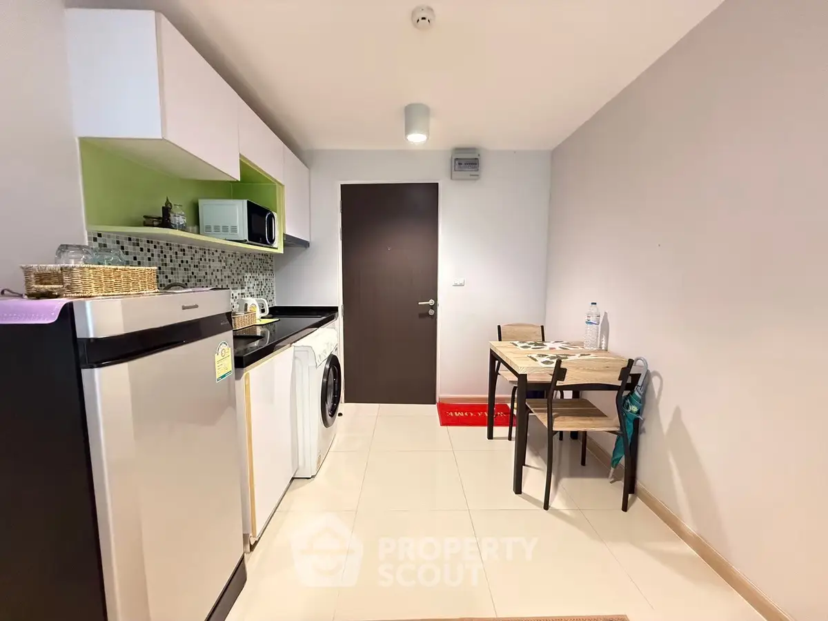 Modern compact kitchen with dining area and washing machine in a cozy apartment.