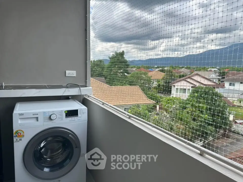 Balcony with washing machine and scenic view of suburban homes and mountains.