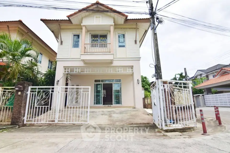 Charming two-story house with gated driveway and lush greenery in a serene neighborhood.