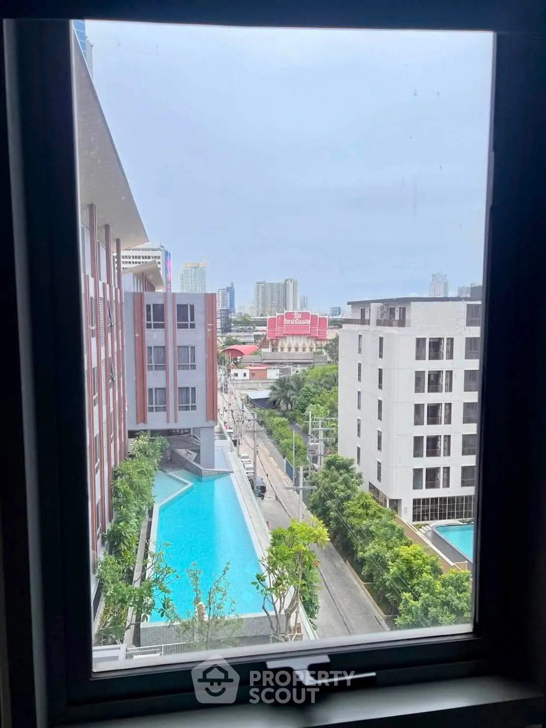 Stunning cityscape view from a high-rise window overlooking modern buildings and a refreshing pool.