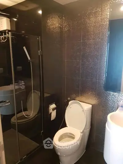 Modern bathroom with sleek black tiles and glass shower enclosure