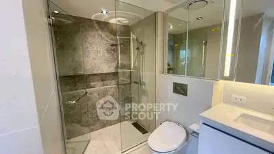 Modern bathroom with glass shower and sleek fixtures in luxury apartment.