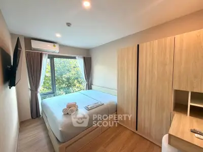Modern bedroom with large window and wooden furniture, featuring a cozy bed and natural light.