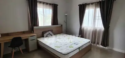 Spacious bedroom with natural light, featuring a comfortable bed and a stylish desk.