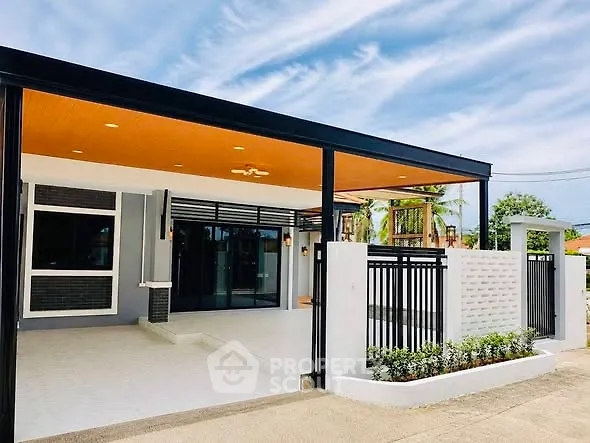 Modern single-story home with sleek black and white exterior, spacious driveway, and lush greenery.