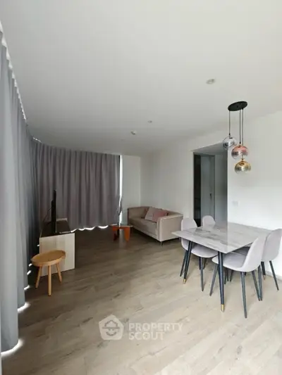 Modern living room with stylish dining area and elegant lighting fixtures.