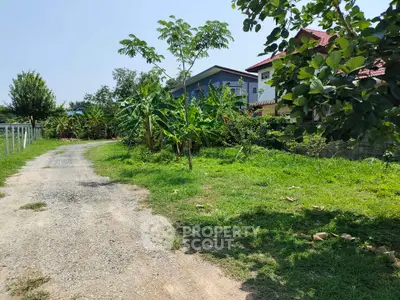 Charming rural property with lush greenery and a gravel driveway leading to a cozy home.