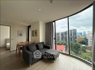Spacious living room with floor-to-ceiling windows offering stunning city views, modern furniture, and elegant decor.