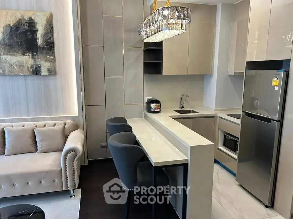 Modern open-layout kitchen with sleek cabinetry and elegant living area featuring plush sofa and stylish decor.