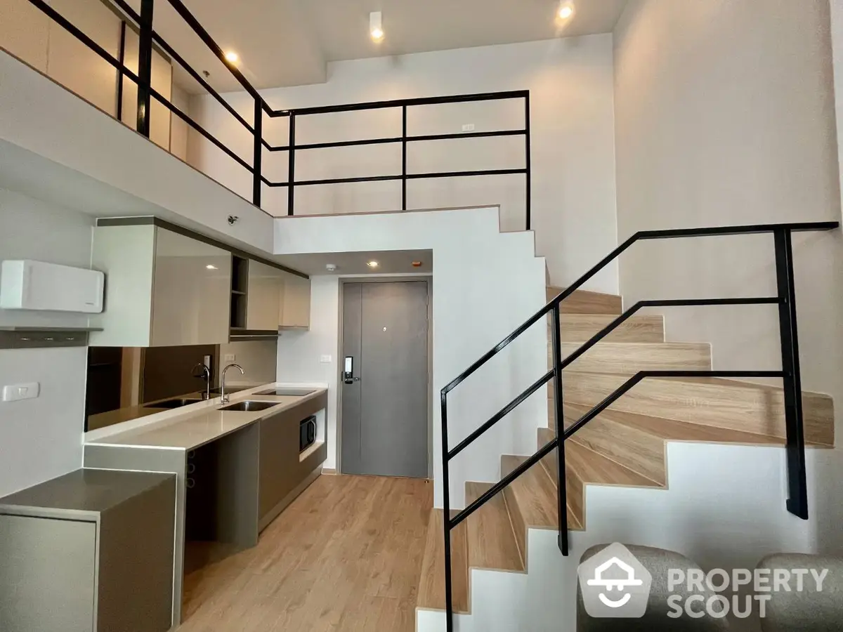 Modern duplex apartment interior with sleek black staircase, open layout kitchen, and wood accents creating a contemporary urban living space.