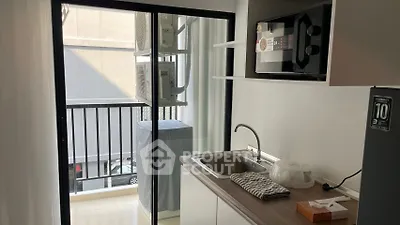 Compact kitchen with balcony access, featuring modern appliances and sleek design for urban living.