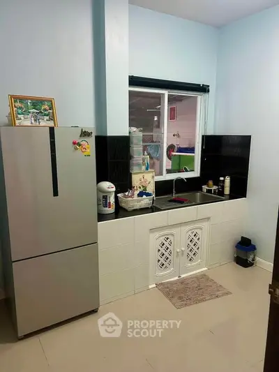 Cozy kitchen with modern fridge and sink area, perfect for small apartments.