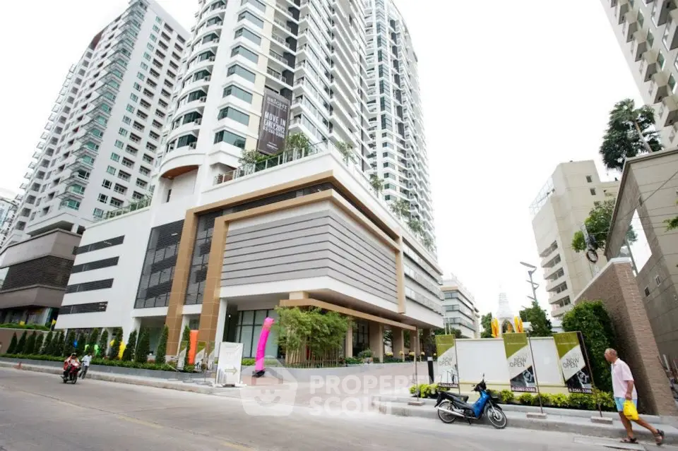 Modern high-rise building with sleek design and lush landscaping in urban setting.