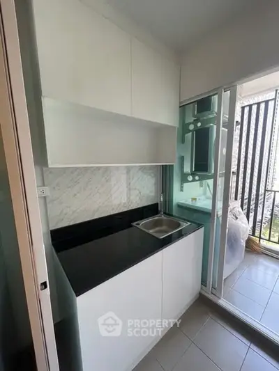 Modern compact kitchen with sleek cabinetry and balcony access