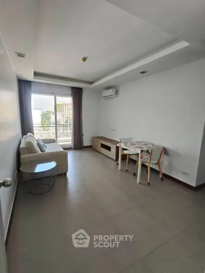 Spacious living room with modern furniture and large window offering city views.