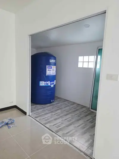 Spacious storage room with large blue water tank and tiled flooring