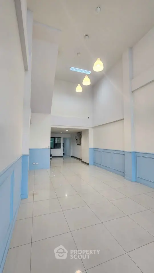 Spacious high-ceiling interior with modern lighting and tiled flooring, perfect for versatile living or commercial use.