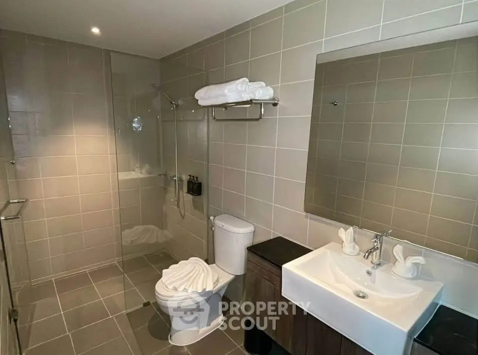 Modern bathroom with sleek design, featuring a glass shower, stylish sink, and elegant tile work.